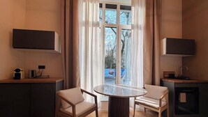 A modern room with a round glass table, two chairs, a TV on the wall, and a view of the outdoors. - Villa Weitmar: Private spa - sauna and designer bathtub (Bochum)