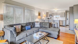 Ein Wohnzimmer mit Ecksofa, Couchtisch und einer Küche im Hintergrund.