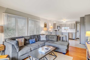 A living room with a sectional sofa, a coffee table, and a kitchen in the background. - Ideal Island Villa with Shared Pool, Beach Access, Free WiFi, Private Balcony & More (Hilton Head)