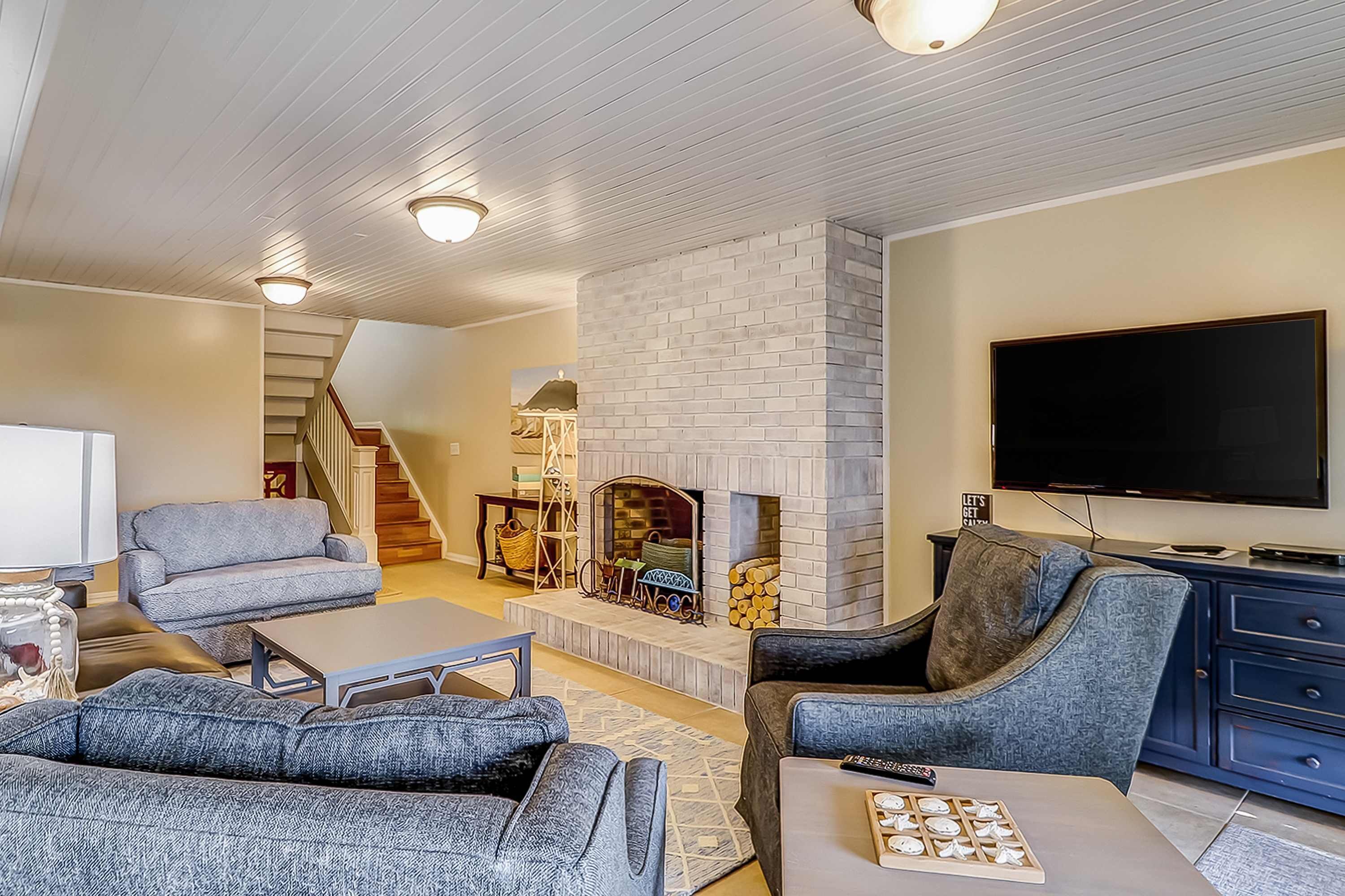 A living room with a fireplace, sofas, a TV, and a staircase.