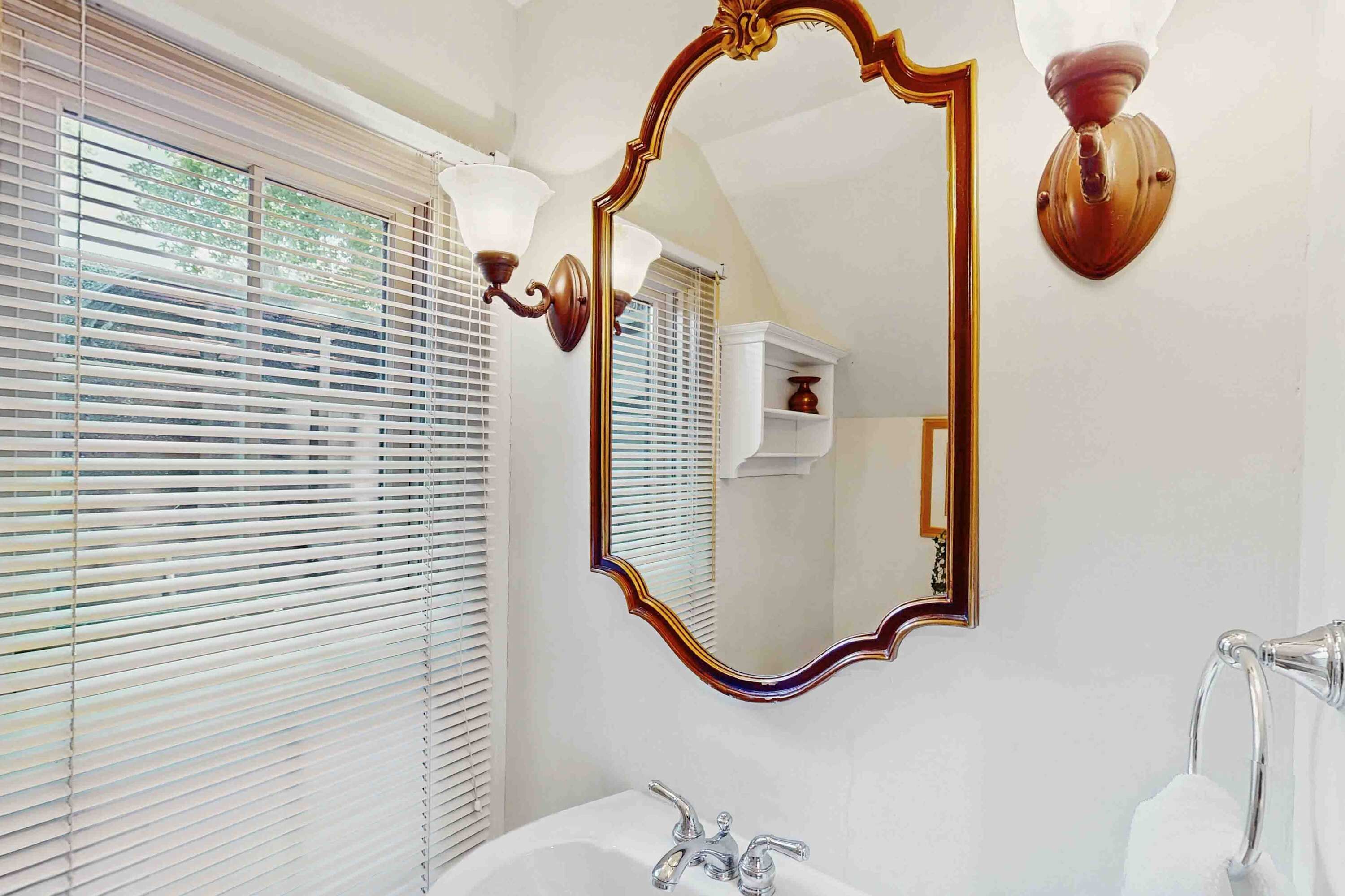 A bathroom with a large mirror, a sink with a faucet, and a towel rack.