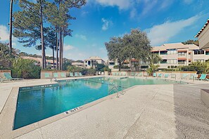 Ein Schwimmbecken mit Liegestühlen und Blick auf Wohnhäuser.