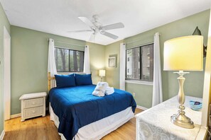A bedroom with a bed, a nightstand, a lamp, and a ceiling fan.