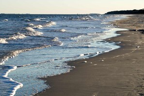 A beach with waves, a clear sky, and a distant shoreline. - Updated Harbour Town Hideaway with Pool & Balcony, Walk to Shops & Golf (Hilton Head)