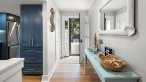 Una cucina moderna con mobili blu scuro, un frigorifero in acciaio inossidabile e un tavolino blu chiaro con oggetti decorativi.