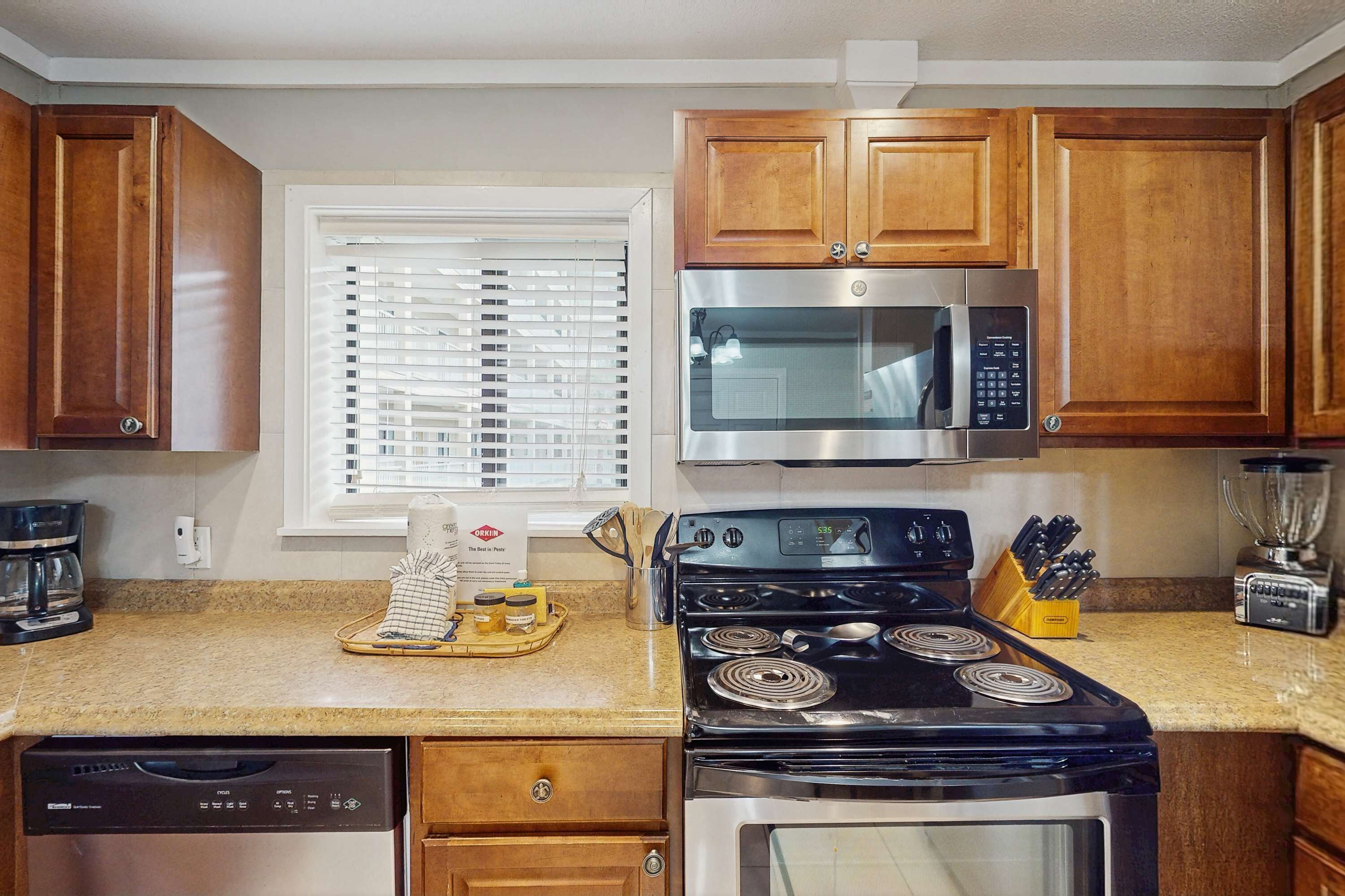 Una cocina con armarios de madera, microondas integrado, estufa y lavavajillas.