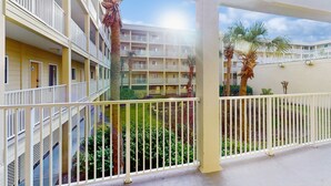 Un hôtel à plusieurs étages doté de balcons, une cour intérieure agrémentée de palmiers et un ciel dégagé.