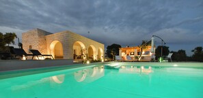 A swimming pool with lounge chairs, a stone building with arches, and a well-lit outdoor area. - Villa LàMìa Donnagnora in Ostuni, heated pool, pets allowed (Ostuni)
