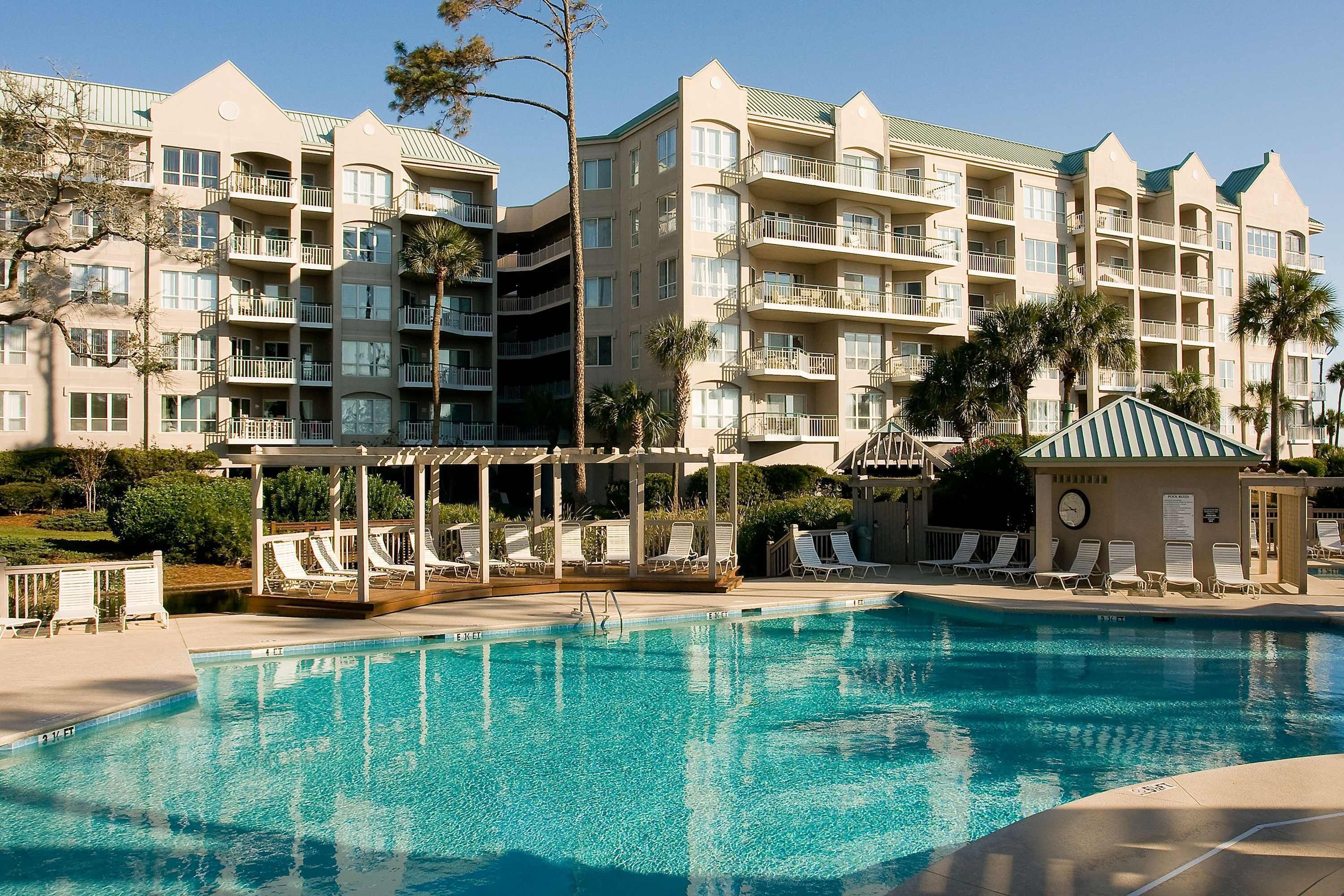 A hotel with a swimming pool, multiple balconies, and a gazebo.