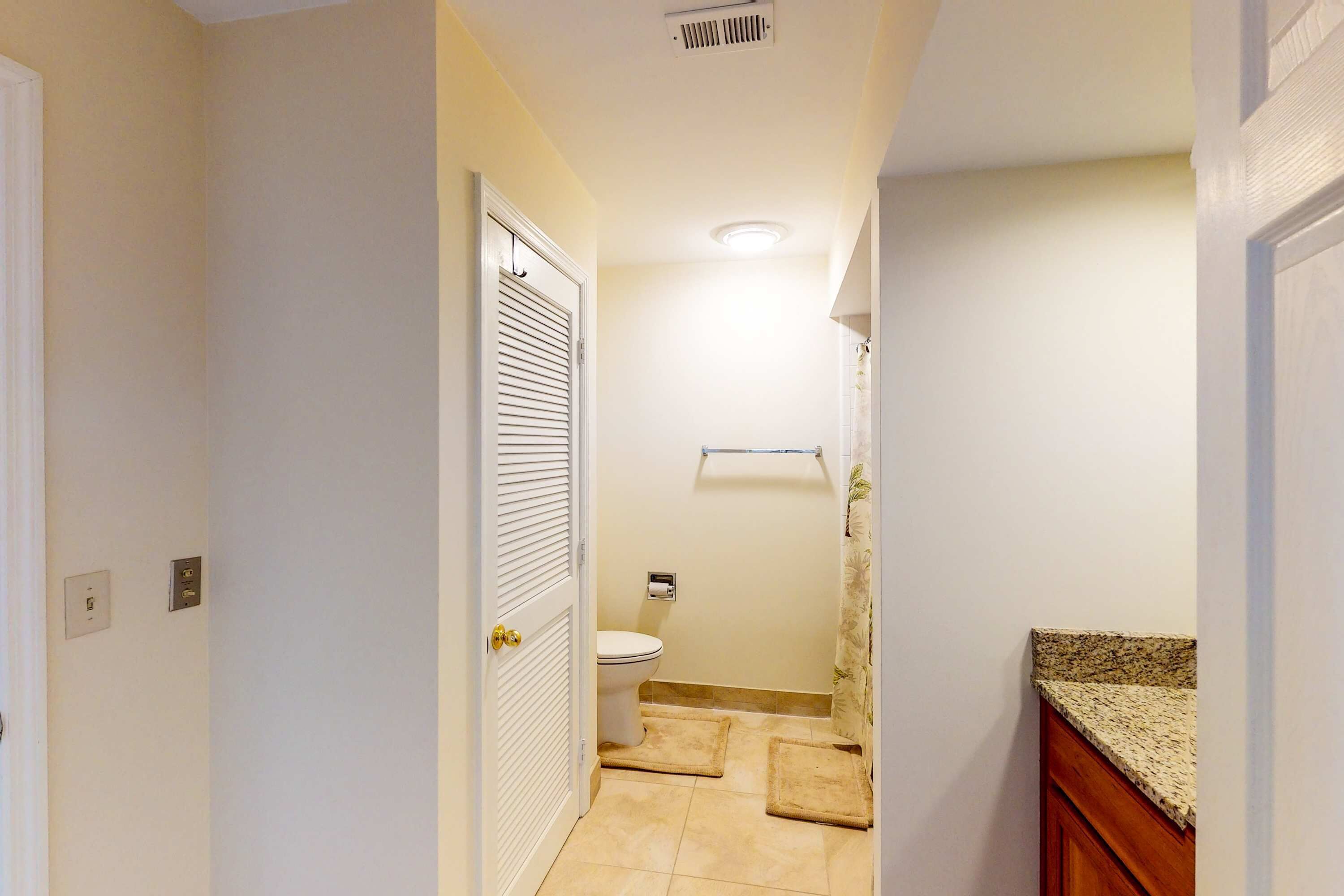A narrow hallway leading to a bathroom with a toilet, a towel rack, and a shower curtain.