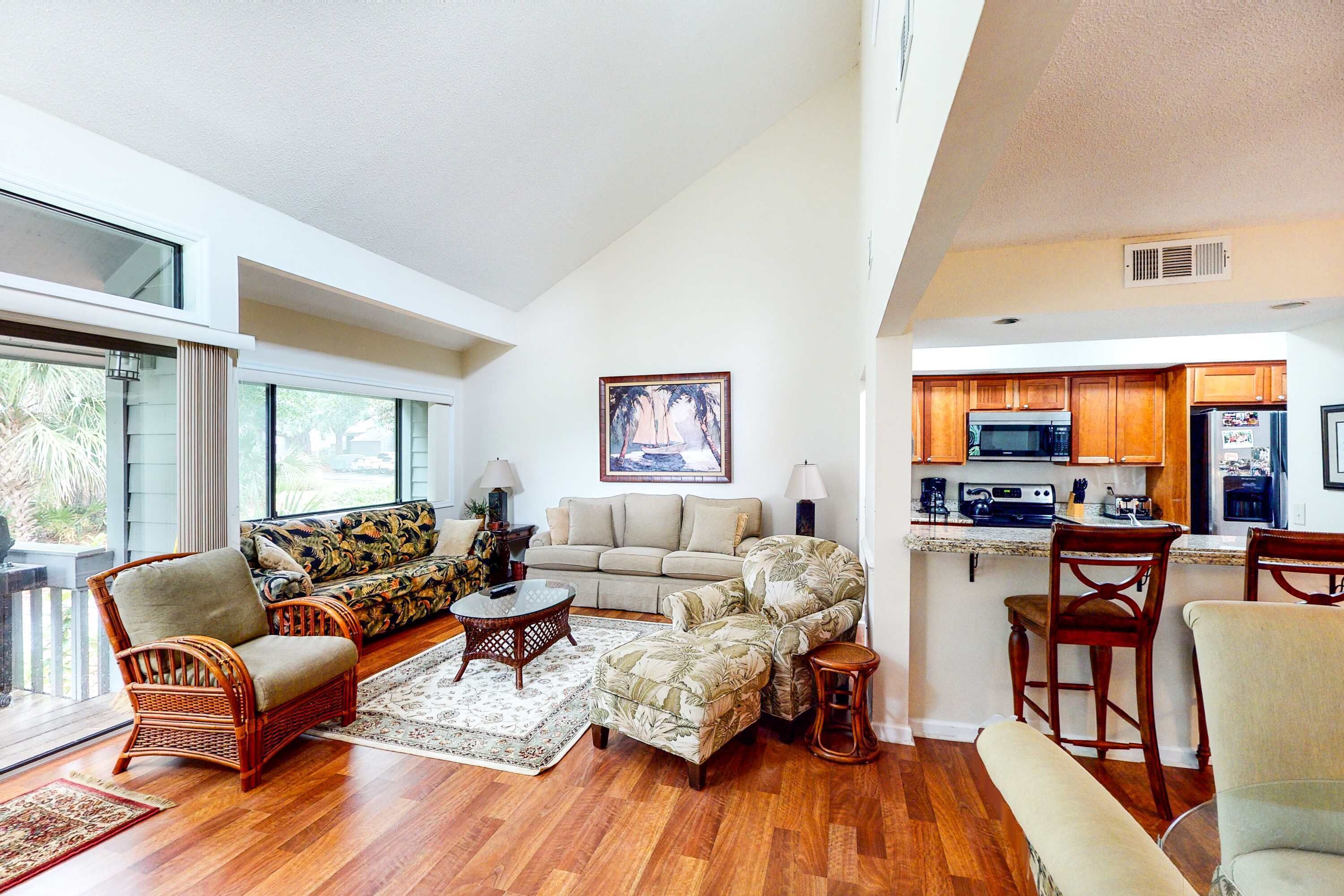 A spacious living area with a sofa, chairs, a coffee table, and a kitchen area with a refrigerator and microwave.