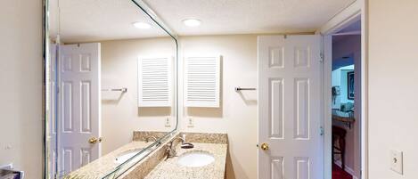 A bathroom with a double sink, a large mirror, and a potted plant.