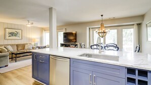 Een moderne keuken met een marmeren aanrechtblad, een inbouw vaatwasser en een groot raam.