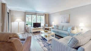 Ein Wohnzimmer mit einer Couch, einem Sessel, einem Couchtisch, einem Fernseher und Kunstwerken an der Wand.