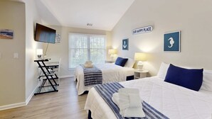 A hotel room with two beds, a desk with a chair, a TV, and artwork on the walls. - Charming French Inspired Villa, Dog Friendly Retreat with Patio, Pool & Tennis (Hilton Head)
