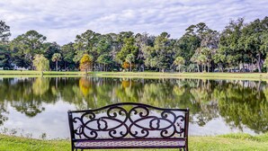 A bench by a calm lake with trees in the background. - Charming French Inspired Villa, Dog Friendly Retreat with Patio, Pool & Tennis (Hilton Head)