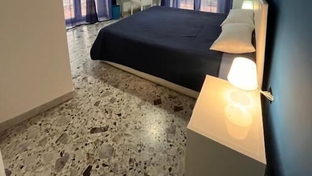 Een slaapkamer met een bed, nachtlampen, een bureau en een televisie.