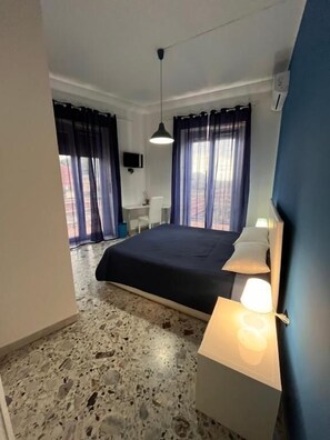 Una camera da letto con un letto, lampade sui comodini, una scrivania e un televisore.