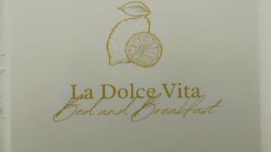Een bord met een illustratie van fruit en de tekst 'La Dolce Vita Bed and Breakfast'.