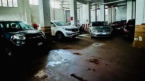Een parkeergarage met verschillende auto's, betonnen pilaren en een betegelde vloer.