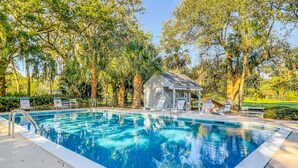 A swimming pool with lounge chairs, a small building, and surrounding trees. - Gated community home with lagoon & pools Near Beaches & Dog Friendly (Hilton Head)