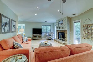 Ein Wohnzimmer mit Sofa, Fernseher, Kamin und einer Wand mit Dekorationselementen.