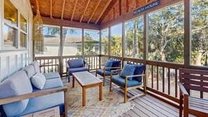 A covered porch with wooden furniture, a ceiling fan, and a view of the surrounding area. - Gas Money (Edisto Beach)