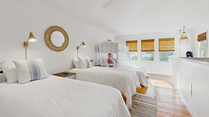 A bedroom with two beds, a ceiling fan, a mirror, bedside lamps, a dresser, and a window with blinds. - Gas Money (Edisto Beach)