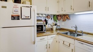 A kitchen with white cabinets, a microwave, a refrigerator, and a sink. - Terrific island escape with pool, furnished patio, fast WiFi & beach nearby (Hilton Head)