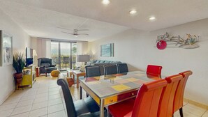 Una sala moderna con comedor, un ventilador de techo y un ventanal grande.