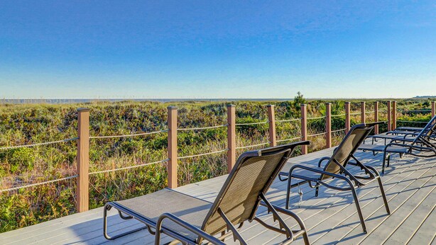 Una terraza de madera con sillas de metal que da a un paisaje natural.