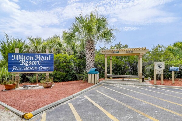 Señal del Resort Hilton Head con un estacionamiento, una pérgola y follaje circundante.