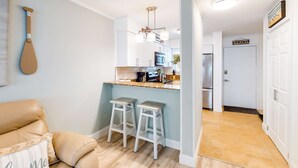 A kitchen with white cabinets, a microwave, and a refrigerator. There are two white stools at the kitchen counter. - Hilton Head Resort Villa with AC, pool, hot tub, tennis - near beach & golf (Hilton Head)
