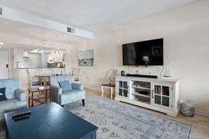 A living room with a flat-screen TV, a coffee table, and a sofa. There is a dining area with a table and chairs in the background. - Waterfront condo with walkable locale, central AC, washer dryer, & shared pool (Hilton Head)