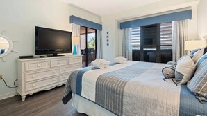 Une chambre d’hôtel avec un lit, une télévision, une commode et une fenêtre avec des rideaux.