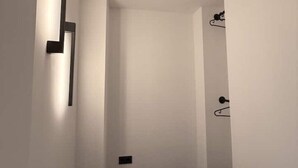 A narrow hallway with a wall-mounted light fixture and a door with a simple handle.