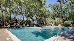 Una piscina circondata da alberi, con cielo sereno sopra.