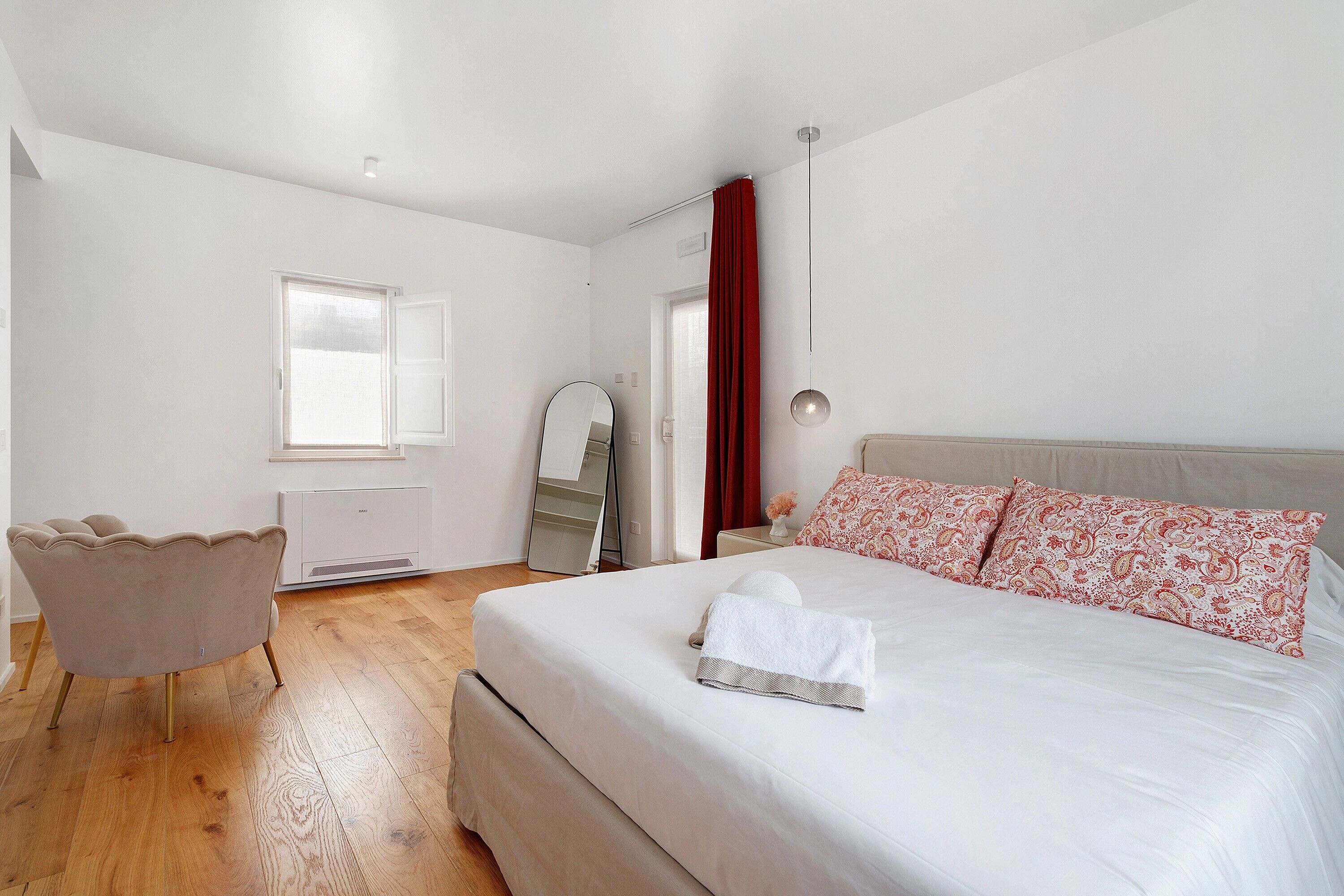 Une chambre à coucher avec un lit, une chaise, une commode et un miroir.