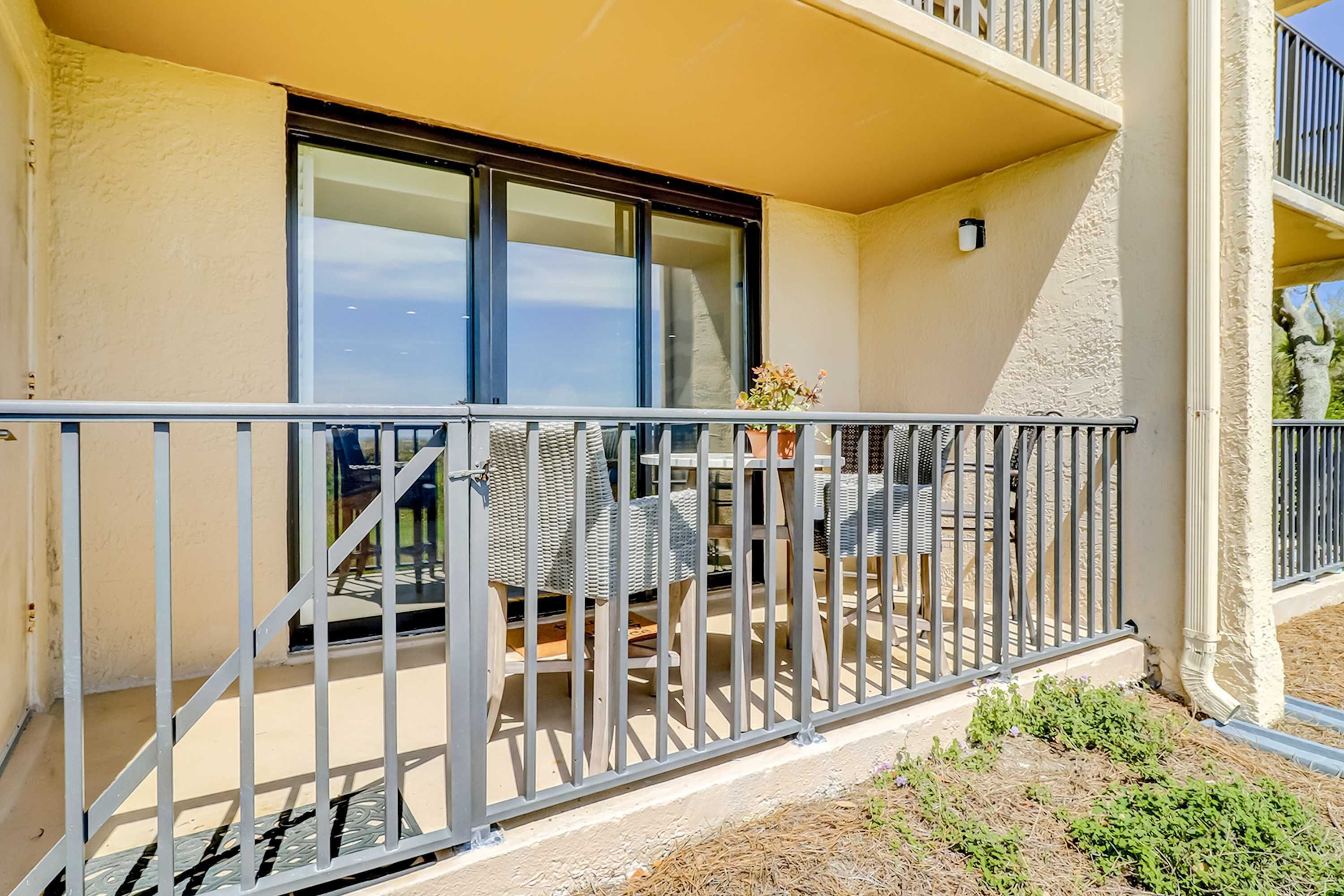 Un balcon avec une table et des chaises, une balustrade et une fenêtre.