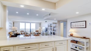 A spacious kitchen with a large island, white cabinetry, and a view to the outside. - Beachfront escape with pools, hot tub, WiFi, washer/dryer, & central AC (Hilton Head)
