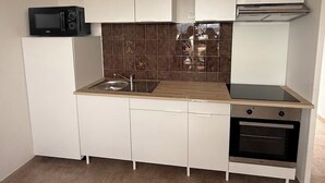 A compact kitchen with white cabinets, a microwave, a sink, a stove, and an oven. - F3 in very quiet villa, large terrace with sea view, beach 5 minutes away on foot (Calcatoggio)