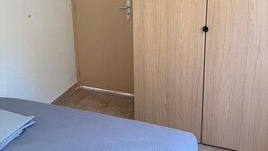 A room with a bed, a wooden wardrobe, and a door. - F3 in very quiet villa, large terrace with sea view, beach 5 minutes away on foot (Calcatoggio)