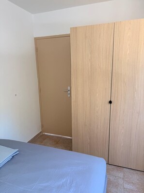 Um quarto com uma cama, um guarda-roupa de madeira e uma porta.