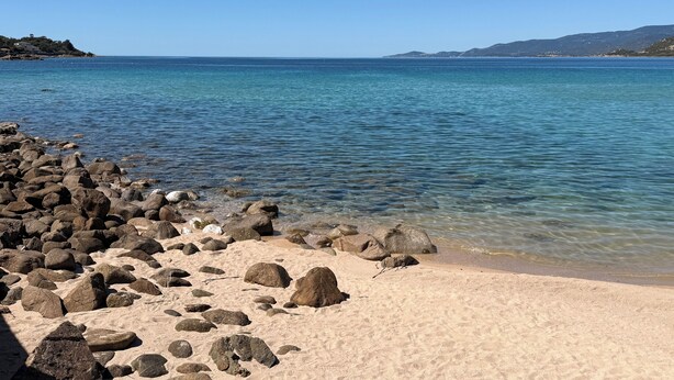 A beach with clear water, rocky shoreline, and distant hills. - F3 in very quiet villa, large terrace with sea view, beach 5 minutes away on foot (Calcatoggio)