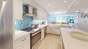 Een moderne keuken met witte kasten, een roestvrijstalen koelkast, een betegelde spatwand en een centraal eiland.