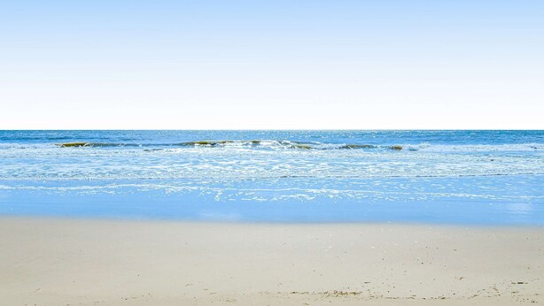 Een strand met helder water en een zandstrand.
