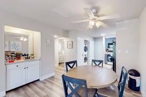 A modern kitchen with white cabinets, a wooden dining table, and a ceiling fan. - 3rd floor condo with private balcony, AC, Washer and Dryer, on site pools, hot tub & tennis (Hilton Head)
