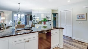 Uma cozinha moderna com uma ilha central, eletrodomésticos embutidos e uma área de jantar com lustre.