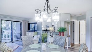 Uma sala de jantar com um candelabro, mesa redonda e cadeiras.