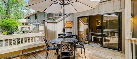 A wooden deck with a round table and chairs, an umbrella, and a sign indicating a restaurant.